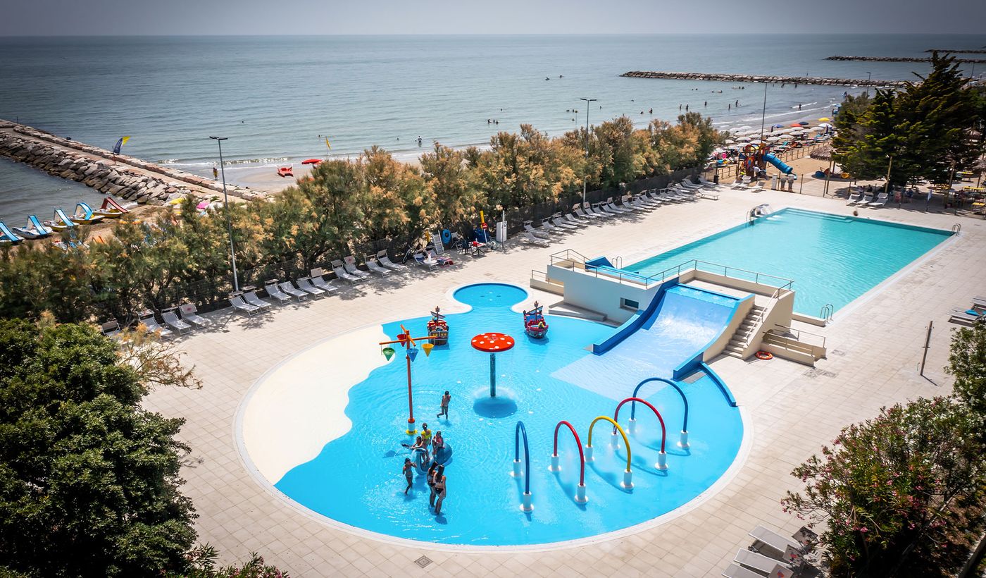 a pool with people in it by a beach